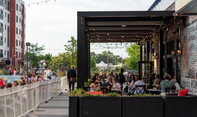 a group of people sitting at tables outside